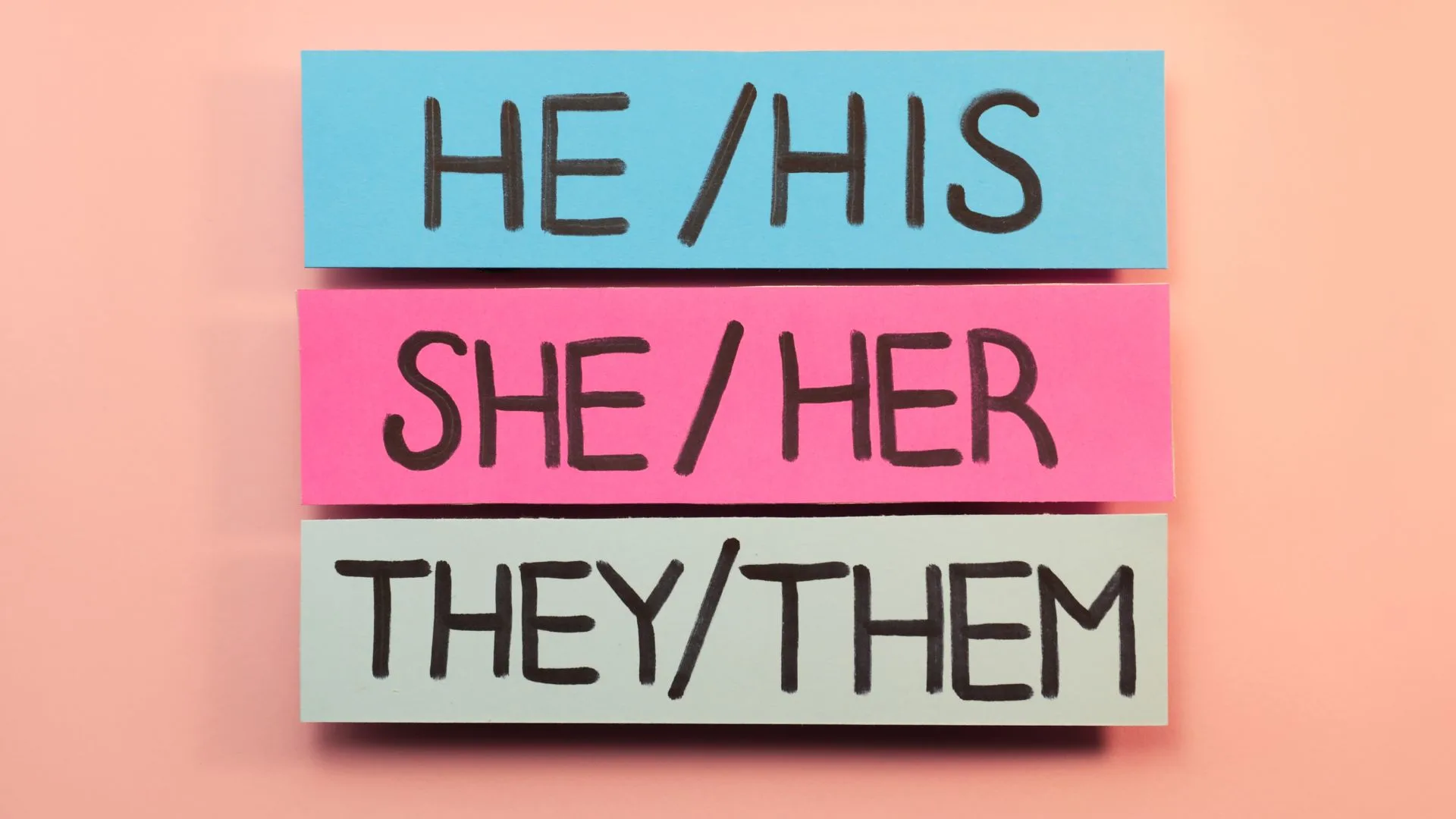 Sheets of paper with pronouns on pink background, flat lay